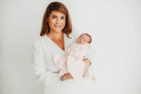 Mother holds her infant daughter during Newborn Portraits at Holy City Babies Portrait Studio in Charleston, SC.