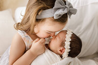 A big sister gives eskimo kisses to her baby sister during the family portion of her newborn session with Jennifer Brandes Photography.