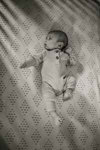 A baby boy lies in his crib.