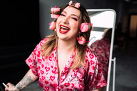 Hair and makeup artist in a vibrant pink editorial look during a creative brand photoshoot.
