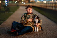 Teenage boy sitting on a walkway with his dog during an evening portrait session in New Bern NC