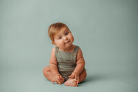 Charleston Baby Milestone Photographer - Baby peers curiously at the camera during his Milestone Portrait Session at Holy City Babies Portrait Studio in Charleston, SC.