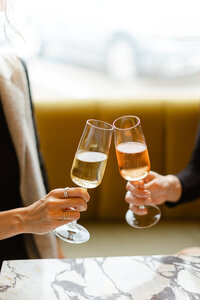 Close up celebrating shot of 2 people holding glasses of champagne and toasting.