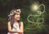 Young fairy girl in Palatka, gazes at a glowing fairy leaving a trail of light in the air during a fairy adventure signature session. - A portrait experience by Nature's Child Photography.