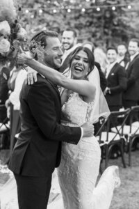 Black and white image of couple hugging and celebrating after just walking back up the aisle taken by southern california wedding photographer Sam Lynn Photo