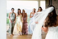 A documentary style wedding photography shot of bridesmaids seeing the bride for the first time, capturing the natural unfolding of the morning.