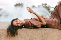 Model reclining on a ledge in front of a fountain, misting overhead