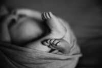 A black and white picture of a newborns toes sticking out a wrap.