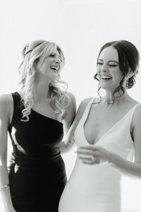 Candid of bride and bridesmaid laughing at Colorado wedding.