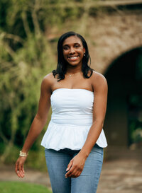 Senior portrait at Bella Sera Gardens in Loxley, Alabama — walking through the courtyard,
laughing.