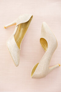 gold bridal shoes on a flat pink background