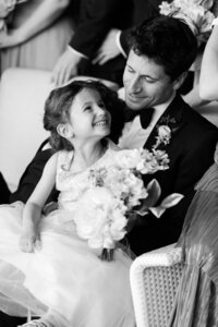Groomsmen holds flower girl in his lap