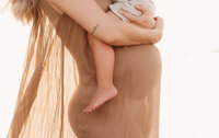 Folly Beach Maternity Photographer -- Pregnant woman poses for Maternity Photos at the Lighthouse Inlet Heritage Preserve on Folly Beach with iconic views of the Morris Island Lighthouse in the distance.
