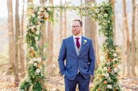 Groom at winter greenery ceremony arbor designed by Flowergirl Cville at Indigo House, Afton, Virginia | Photo by Xiaoqi Li Photography
