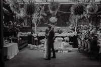 Mariés partageant leur premier baiser sous un lustre suspendu, décor floral abondant et verdure retombante, cérémonie au Richmond, Montréal