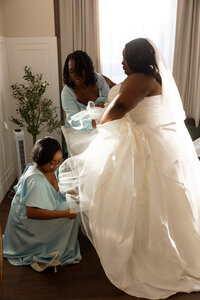 Bride being helped into her dress during a getting-ready moment before the wedding