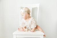 little girl in boho outfit with bow sitting on chair
