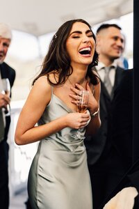 Bridesmaid laughing with champagne flute during reception