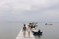 Couple hold hands while walking on dock on Nantucket.