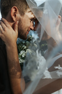 A wedding couple standing forehead to forehead smiling.