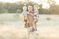 A smiling dad holding his two boys.