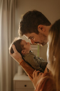 dad and mom snuggling newborn baby