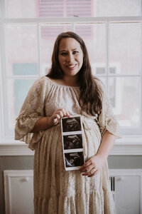 Pregnant woman holding ultrasound images during Amy Mitchell Photoshoot at Maison Charlottesville.