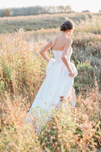 The bride gracefully walks alone through the meadow