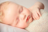 Close up portrait of sleeping newborn baby boy in neutral studio backdrop