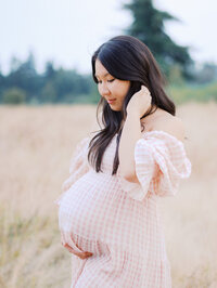 Pregnant asian mom looking pensive in Discovery Park in Seattle
