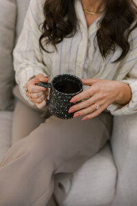 Woman holding a black speckled coffee cup
