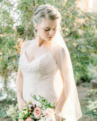 Full body image of Bride holding bouquet looking down to her left