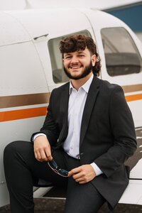 Senior portrait at a small hangar near Mobile International Airport in Mobile, Alabama — posing near airplane