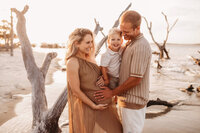 Folly Beach Maternity Photographer -- Pregnant woman poses for Maternity Photos at the Lighthouse Inlet Heritage Preserve on Folly Beach with iconic views of the Morris Island Lighthouse in the distance.