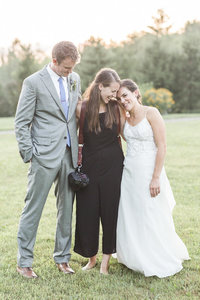 photographer hugging bride and groom