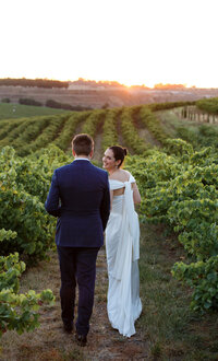 Bride and groom overlooking vineyard at sunset