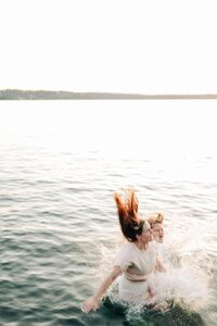A couple, jumping into the water off of a dock.