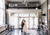 Bride and Groom stealing kisses before their wedding at the Hood River Hotel in Hood River, Oregon with the iconic Mt. Hood Hotel sign above them.