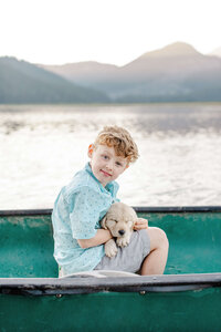 A kid with his pet riding in a boat during family photography in Bend Oregon