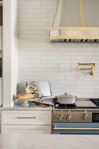daley home sunny bell new construction kitchen with white backsplash tile and gold pot filler