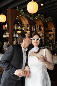 man kissing womans cheek with sun glasses on for detroit bar engagement shoot