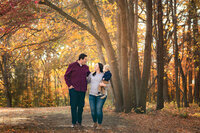 A family of three walks among the beautiful leaves during their fall family session in Southern Minnesota.