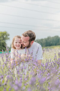 father hugs and snuggles with daughter in lavender field in milan michigan