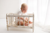 Baby plays with a wooden toy during Baby Milestone Portrait Session at Holy City Babies Portrait Studio in Charleston, SC.