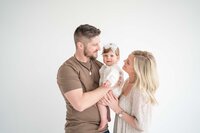 Family with baby girl in white room smile