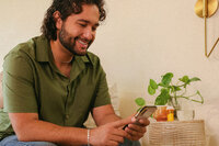 Man on his phone at home during a telehealth check-in