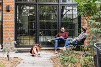 Two dads relaxing in their Toronto backyard while their daughter draws with chalk on the patio