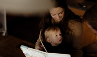 Mom reading to her baby son in a New England farmhouse home. Fine art family photography capturing tender moments.