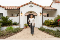 Female entrepreneur walking outside a Spanish-style building during a Ventura County personal brand photography session by photographer Jaclyn Hernandez.