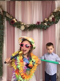Two kids singing and dressed up in props for a photobooth picture